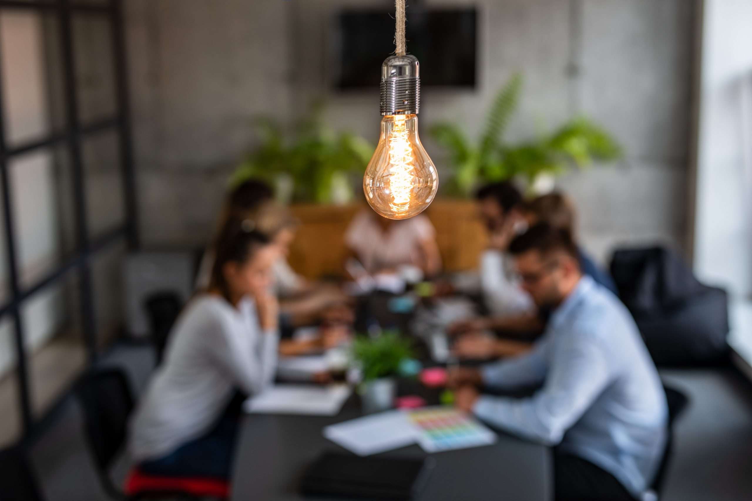 a lightbulb in front of a meeting. Symbolizing innovatio and ideas